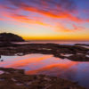 Incredible whispy pink and orange sunrise sky reflected and mirrored in the pool of water at Tamarama Beach.