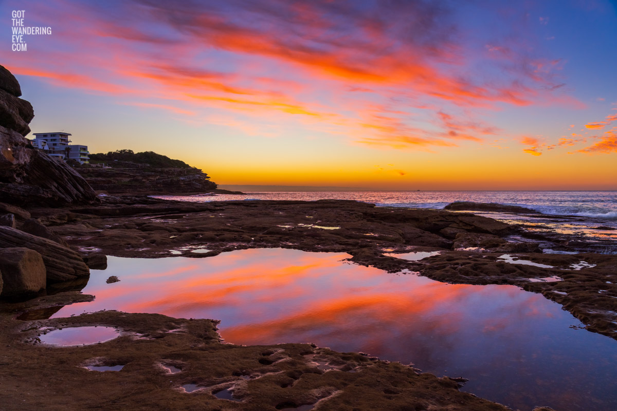 Incredible whispy pink and orange sunrise sky reflected and mirrored in the pool of water at Tamarama Beach.