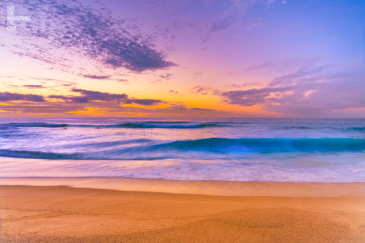 Orange and purple skies rising during sunrise above surfers at Tamarama Beach Sunrise Sydney. Photography by Allan Chan.