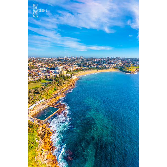 Aerial view on a sunny summers day above the Coogee Coastline Coastal Walk. Sydney city skyline on the horizon with Wylies baths and Giles Baths in foreground.