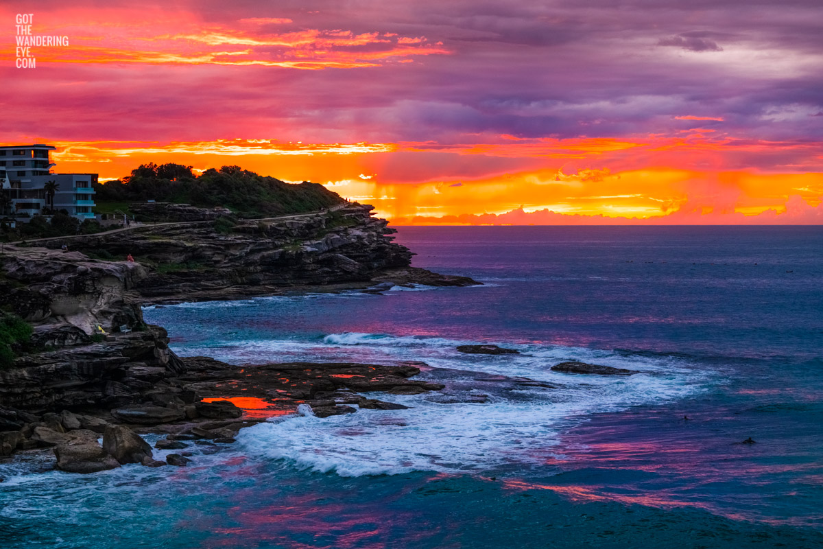 Fiery sunrise orange sky rising above MacKenzies Bay. Tamarama Sunrise of the coastal walk, Sydney.