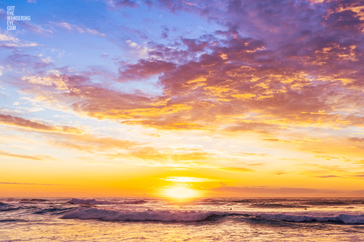 Surfers waiting for waves and watching an incredible orange and yellow puffy cloud Sunrise Tamarama Beach.