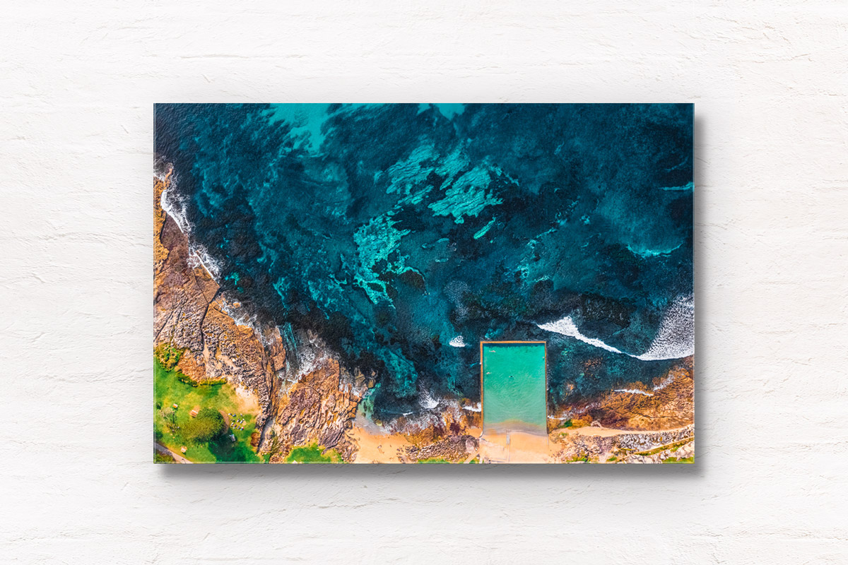 Aerial above the coastline and swimmers doing laps in Shelly Beach rock ocean pool at Cronulla.