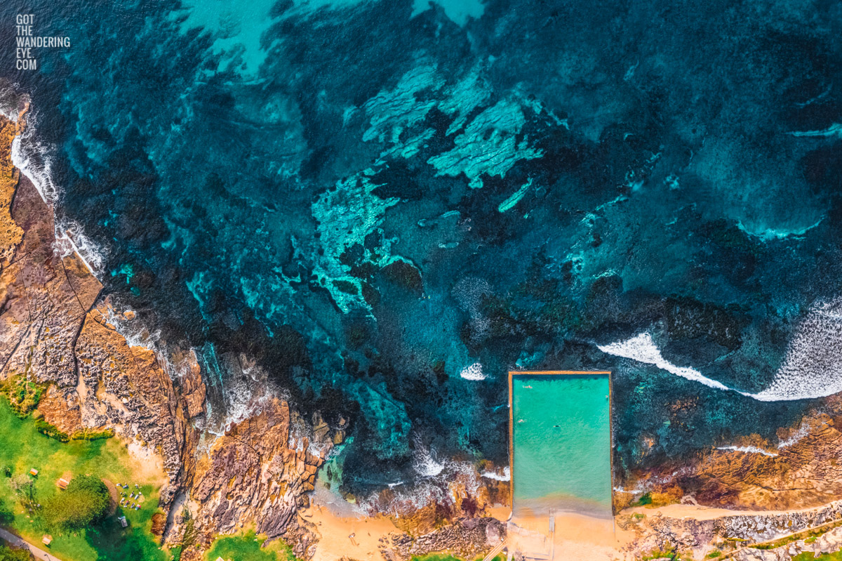 Aerial above the coastline and swimmers doing laps in Shelly Beach rock ocean pool at Cronulla.