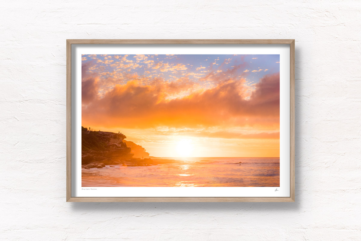 Golden warm light beaming through clouds on a Tamarama Beach Sydney Sunrise, lighting up Mackenzies point clifftops by Allan Chan.