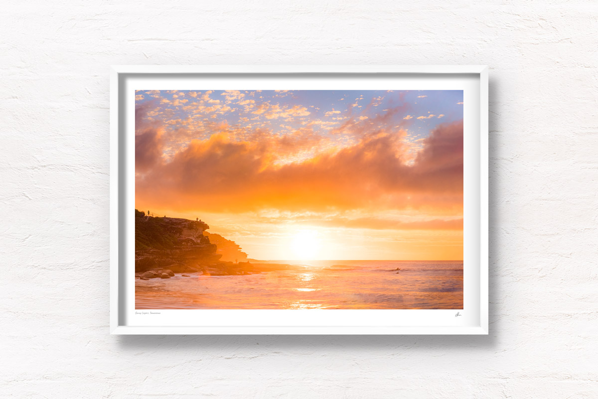 Golden warm light beaming through clouds on a Tamarama Beach Sydney Sunrise, lighting up Mackenzies point clifftops by Allan Chan.
