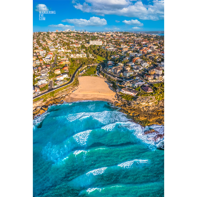 Tamarama Beach Aerial Photography. Pumping waves and the view looking back towards the Sydney City skyline on a clear blue sky day.