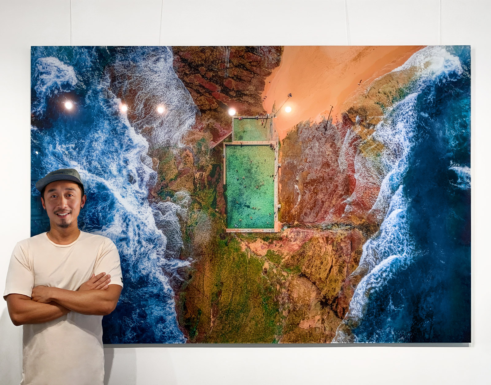 Allan Chan, travel photographer, creative director & brand designer from Gotthewanderingeye. Standing in front of the Hey Mona acrylic wall art print.