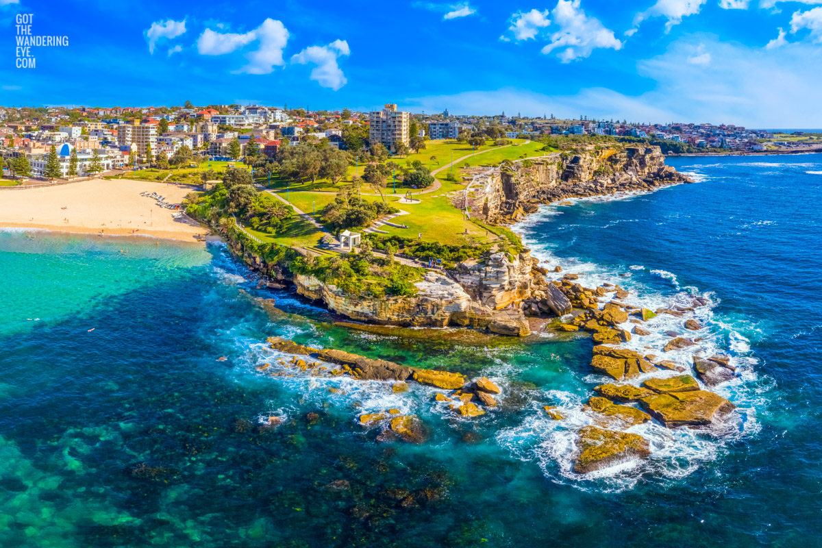Aerial view looking back at Dolphins Point Coogee clifftops, and the iconic Giles Baths ocean rock pool and Coogee Pavillion in Sydney.