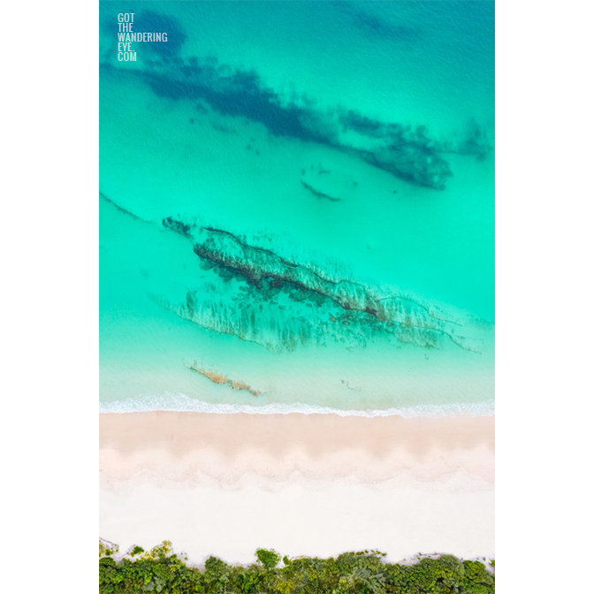 Aerial view above the teal coloured ocean and pure white sand of Hyams beach in Jervis Bay in Summer.