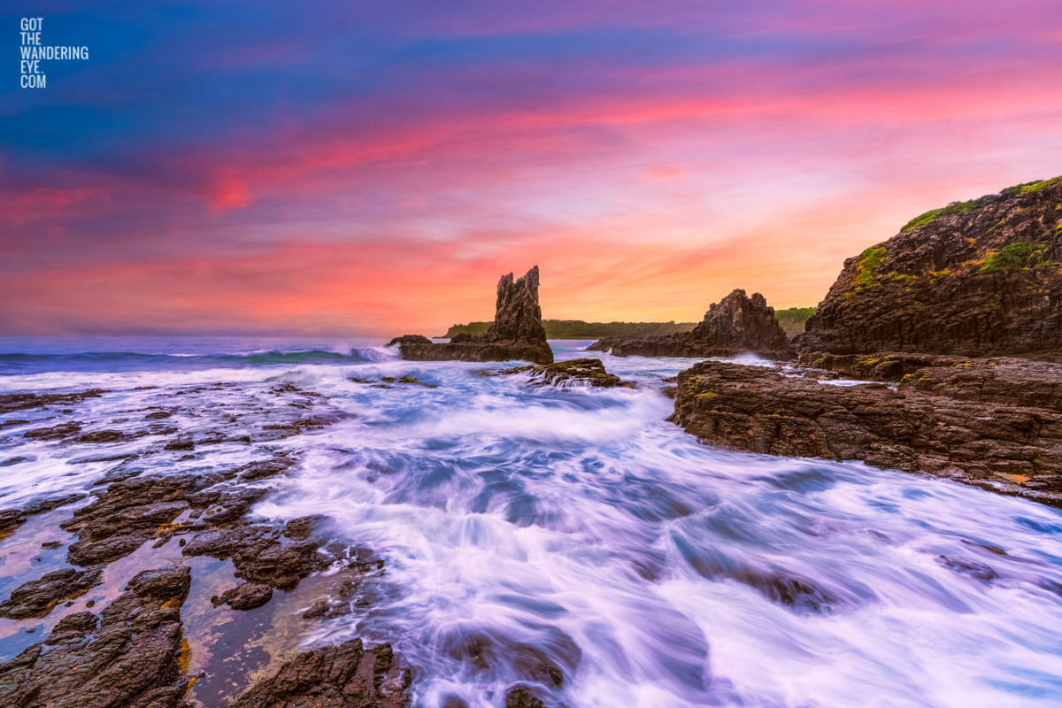 Long exposure of waves crashing over the rocks during a pink sky sunrise at Cathedral Rocks, Kiama Downs.