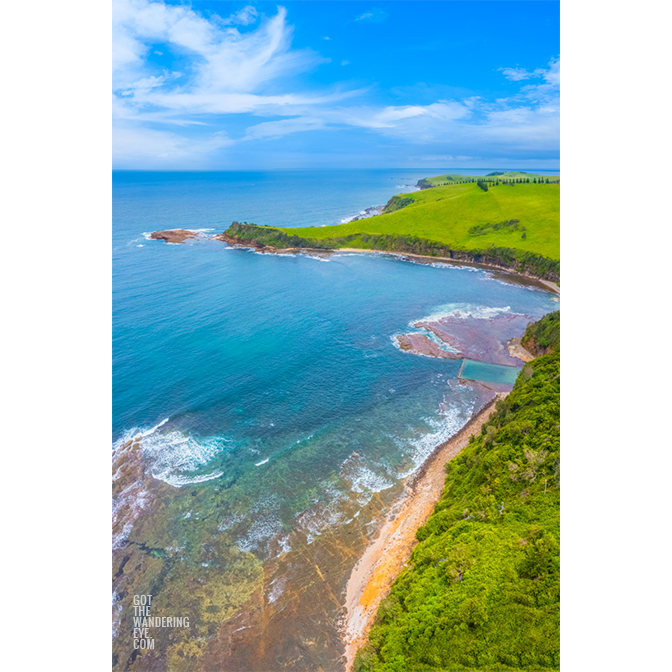 Aerial view above Gerringong Boat Harbour rock pool and rolling green headland in the NSW South Coast.