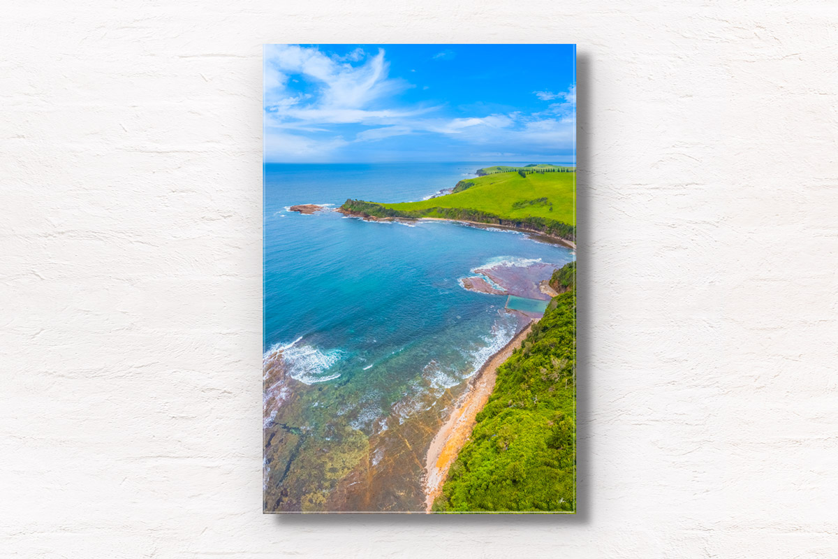 Aerial view above Gerringong Boat Harbour rock pool and rolling green headland in the NSW South Coast.