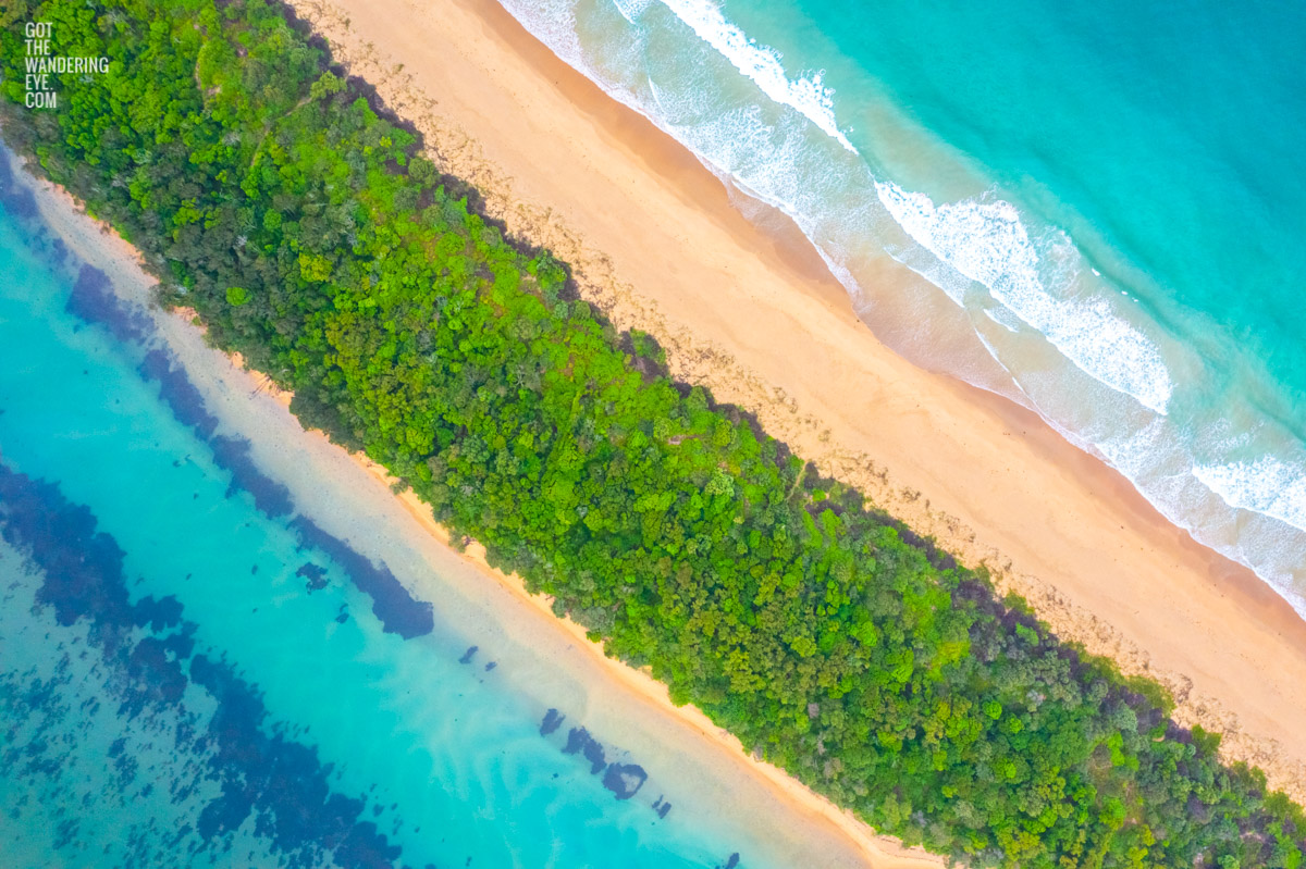 Beautiful split view above the turquoise water above Minnamurra Beach and Minnamurra River. Bushland surrounded by water.