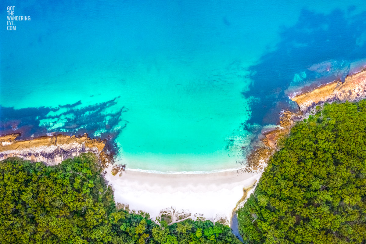 Aerial view above Greenfield Beach in Jervis Bay. The pure white sand surrounded by bushland and teal crystal water.