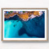 Aerial view above the blues of north Bondi Boat sheds and crystal clear ocean surrounding flat rock.