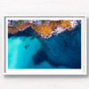 Aerial view above the blues of north Bondi Boat sheds and crystal clear ocean surrounding flat rock.