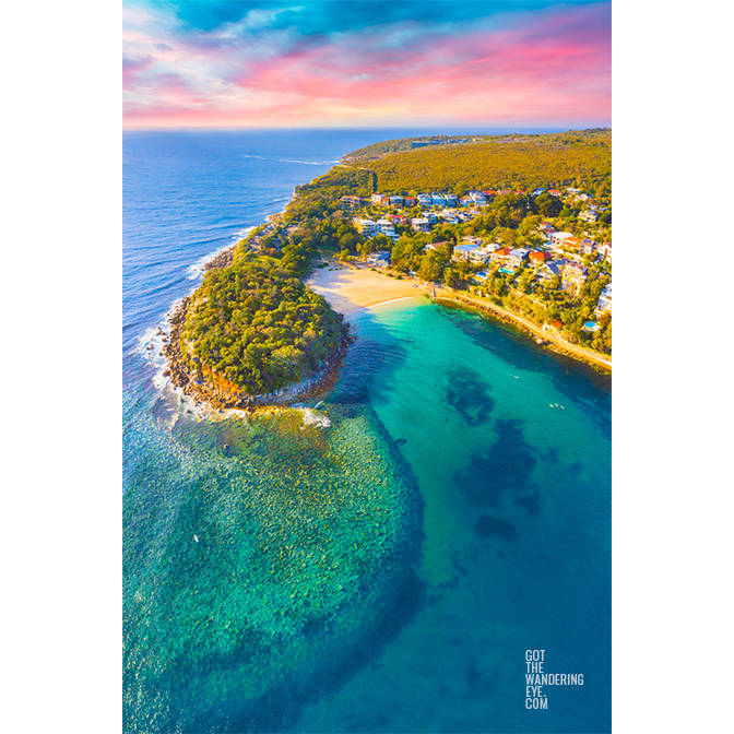 Aerial view of a gorgeous warm sunrise illuminating the teal ocean and Shelly Beach on an early morning.
