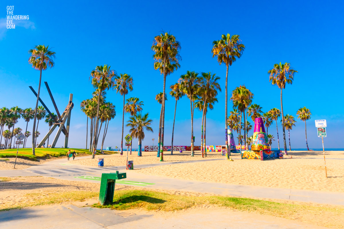 Surfers walking across the Venice Beach boardwalk in California.