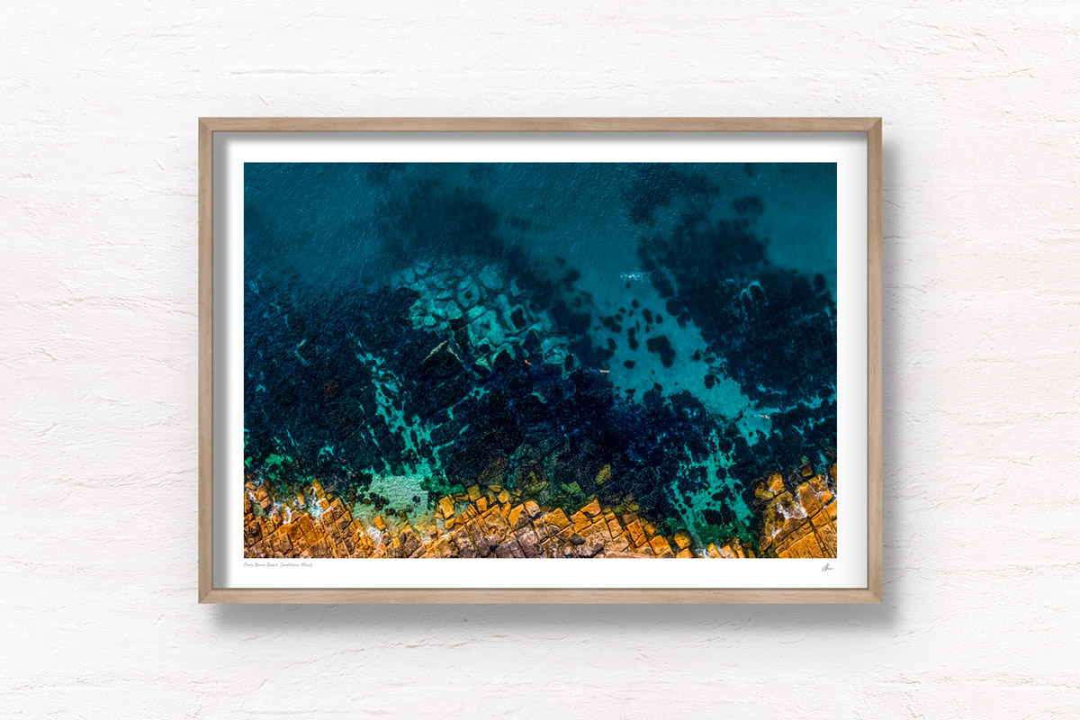 Aerial top down view above swimmers at Fairy Bower Beach's crystal clear waters. Framed art photography wall art print by Allan Chan.