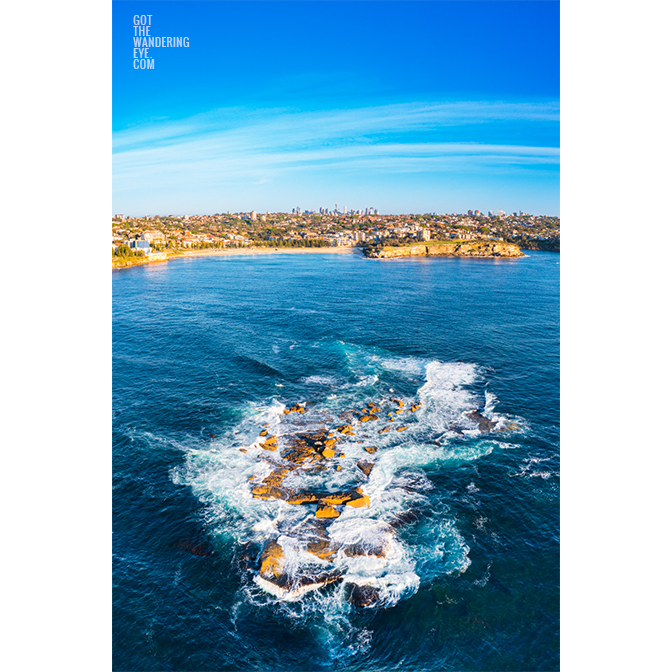 Aerial view above Wedding Cake Island looking back towards Coogee Beach on a Sunny day.