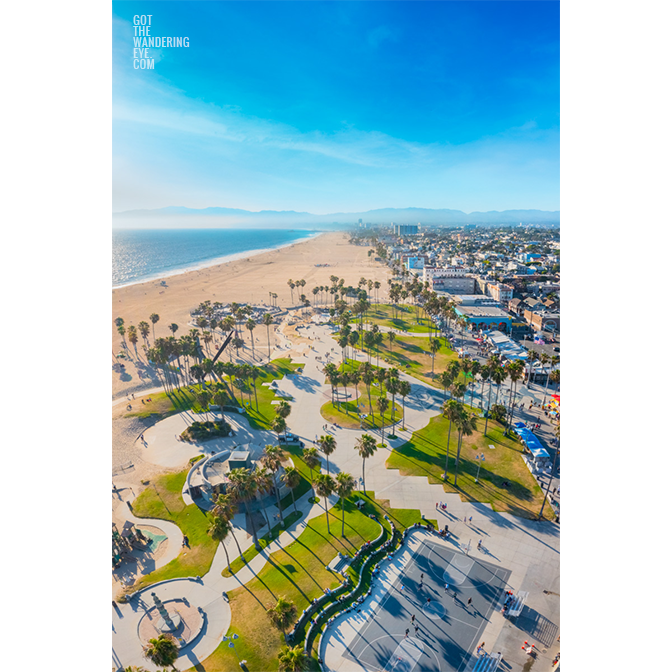 Aerial view above Venice Beach Boardwalk overlooking the basketball court towards Santa Monica Pier..